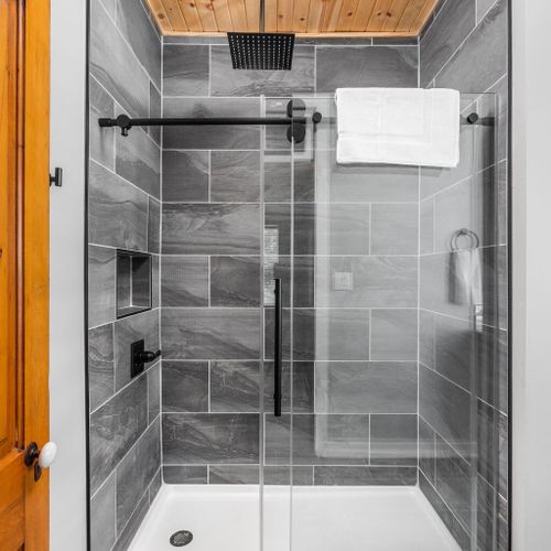 Elegantly tiled shower, accompanied by shampoo, conditioner, and body wash. Wrap yourself in the comfort of fresh, laundered towels for a truly rejuvenating experience.