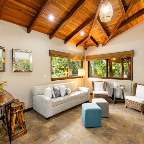 Casita reading nook — small sofa, two wicker chairs, framed tropical art.