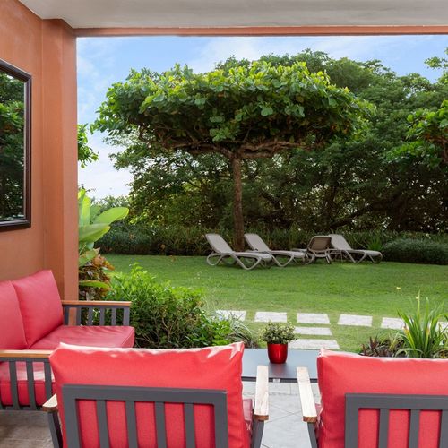 Tropical garden and pool view from spacious balcony at Playa Langosta condo in Tamarindo, Costa Rica. Lush greenery, resort-style pool, outdoor seating, ocean breeze. Ideal for morning coffee, reading, and enjoying paradise.