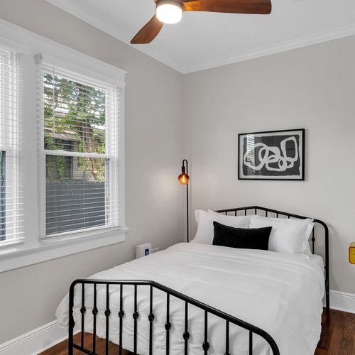 Wake up to soft daylight in this bedroom w/ an iron bed, crisp linens & modern art