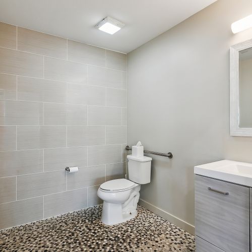 Bathroom w/ toilet, sink & neutral tile.