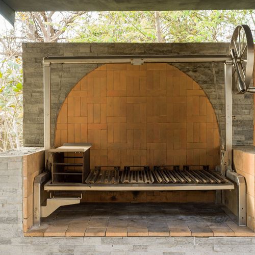 Argentinian asado grill - hand-cranked grate, brick firebox - the centerpiece for live-fire feasts.