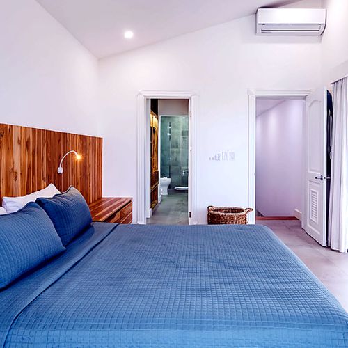 Teak walls, tall ceilings, ocean air — the kind of room that makes you sleep in.