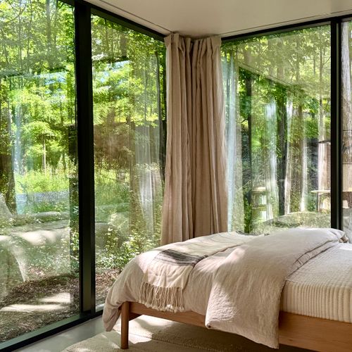 Wake up in the treetops — the bed sits within wraparound glass and greenery.