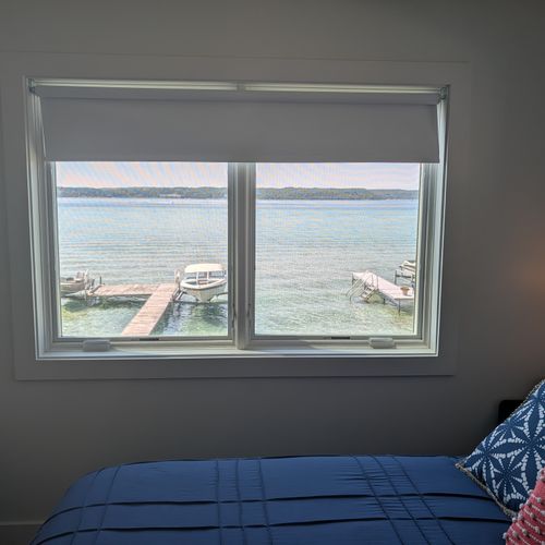 BEDROOM #1 (SECOND FLOOR):  Features a queen-size bed, nightstands, lamps, ceiling fan, mini-split A/C unit, television, dresser, closet, mirror, and a great view of Crystal Lake!