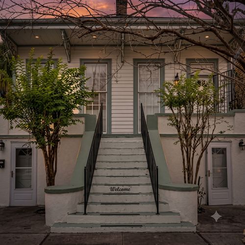 Lush courtyard entrance w/ towering trees & a classic staircase to welcome you home.