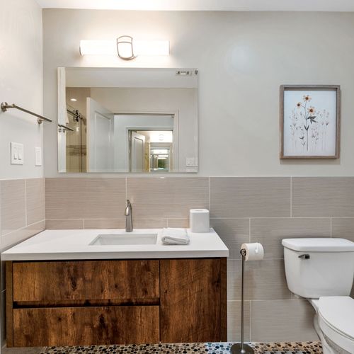 Framed art and a sleek mirror for a polished bath