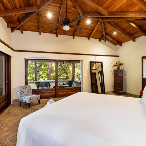 Upper balcony view past terracotta roof tiles to private beach path and Tamarindo Bay at Casa Blue Lagoon, Costa Rica.