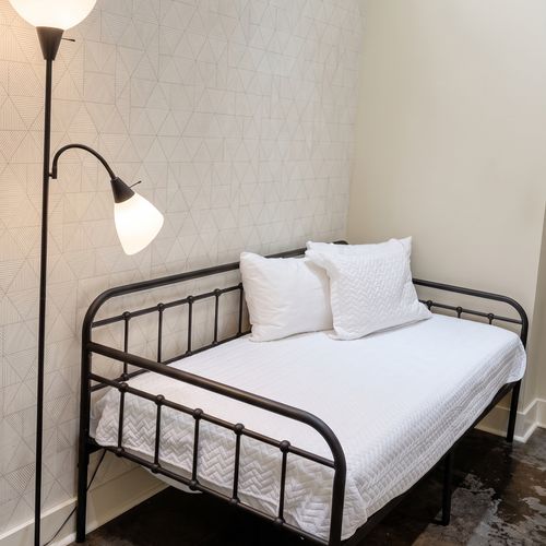Cozy bed with comfortable bedding and bedside lamp