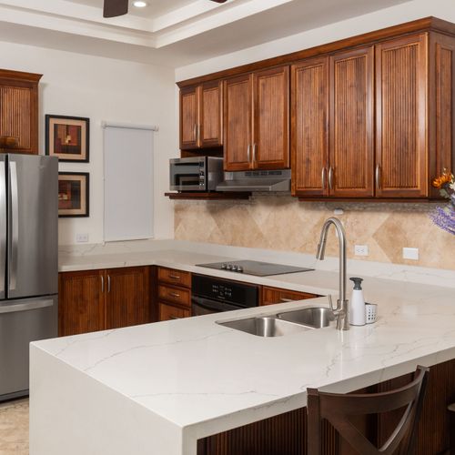 Modern fully equipped kitchen with stainless steel appliances, coffee maker, blender, and cookware at luxury Playa Langosta condo, Tamarindo, Costa Rica. Perfect for preparing delicious family meals during your stay.