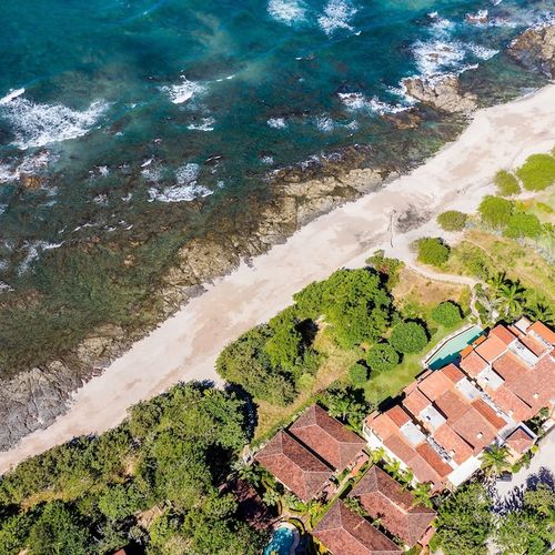 Aerial view of luxury Playa Langosta beachfront complex in Tamarindo, Costa Rica. Turquoise ocean, Las Baulas National Park, lush tropical nature, pool tide, and pristine coastline. Ultimate Guanacaste paradise for nature lovers and beach seekers.
