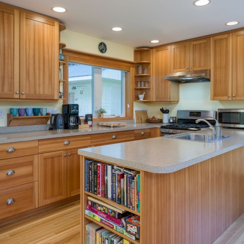 Cook and gather with ease in the kitchen featuring a large island, gas range, full-size refrigerator, microwave, coffee maker, electric kettle, toaster, cookware, dishes, utensils, cutting boards, and a selection of board games for family fun.