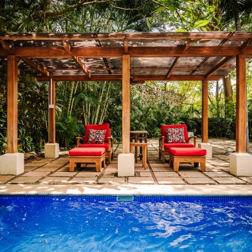 Elegant view from the house with cozy bungalow beyond the pool at this exclusive villas Tamarindo. Comfortable seats surrounded by lush garden and deep nature. Perfect for relaxation, birdwatching, and enjoying Costa Rica's tropical paradise.