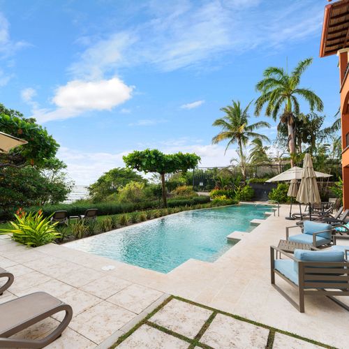 Resort-style crystalline pool surrounded by sun loungers and palm trees at luxury Playa Langosta condo in Tamarindo, Costa Rica. Heated turquoise water, tranquil atmosphere, and direct access to beach for ultimate tropical escape.