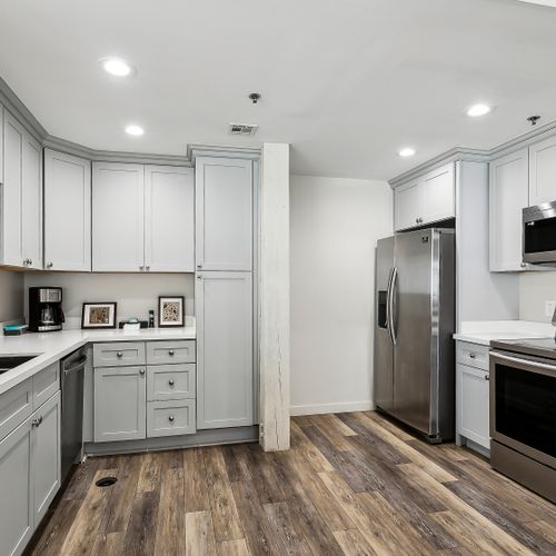 Full kitchen w/ light cabinets, stainless fridge & tile backsplash.