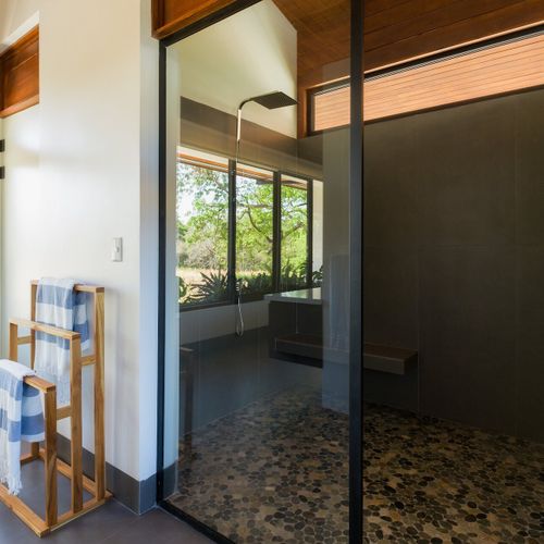 Luxury walk-in rainfall shower with glass enclosure, pebble-stone floor and jungle view at Casa Oso luxury villa, Tamarindo, Costa Rica.