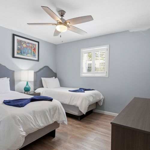 Unit 205 secondary bedroom w/ twin beds & a calm, neutral palette.