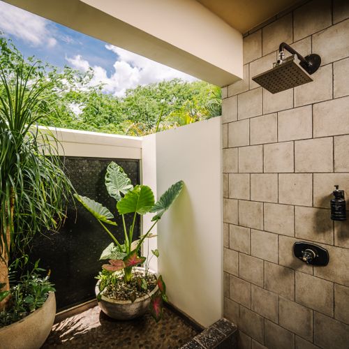 Open concept outdoor shower surrounded by tropical gardens at a luxury Playa Langosta vacation rental in Tamarindo, Costa Rica. Spa style design and natural atmosphere create a relaxing experience for beach house living and coastal stays.