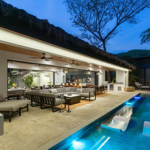 Open-concept great room with chef kitchen, dining for 10 and multiple lounges open to the pool deck at dusk, Casa Oso, Tamarindo.