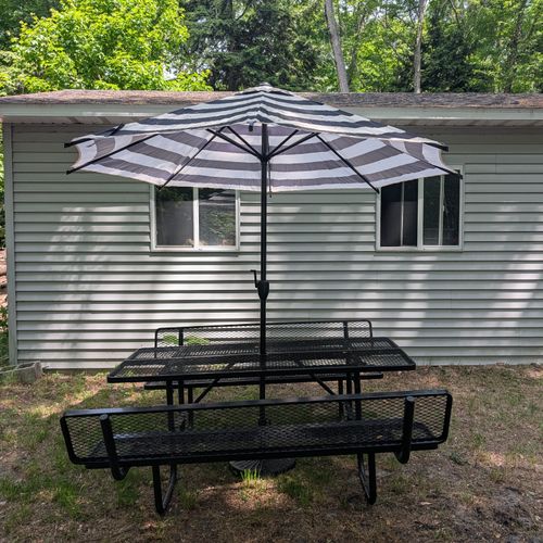 EXTERIOR: The cute metal picnic table and umbrella. Amazing for eating outside on a nice day! The garage behind is not for guest use