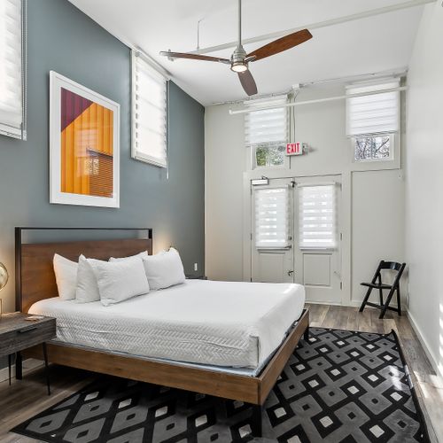Stylish bedroom w/ statement art, bed & patterned rug.