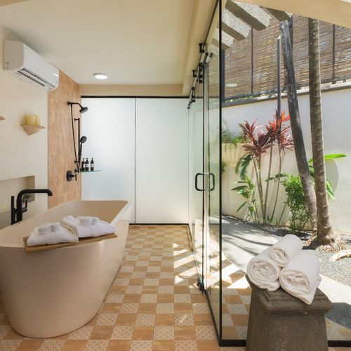 Spa-style ensuite - freestanding soaking tub, walk-in rainfall shower, private tropical courtyard view.