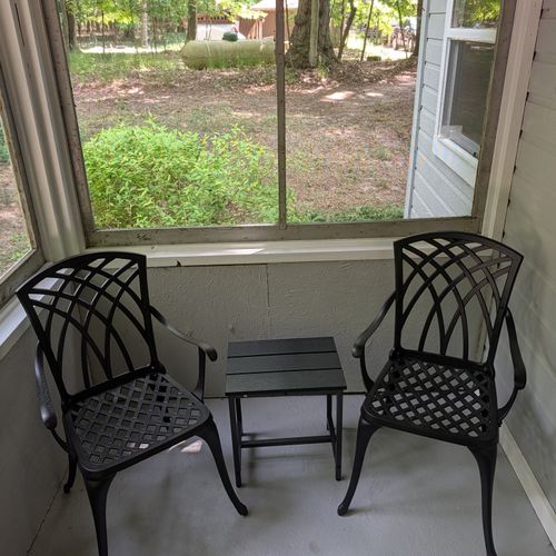 BACK PORCH: The cute screened-in back porch offering metal furniture and a view to the back of the property
