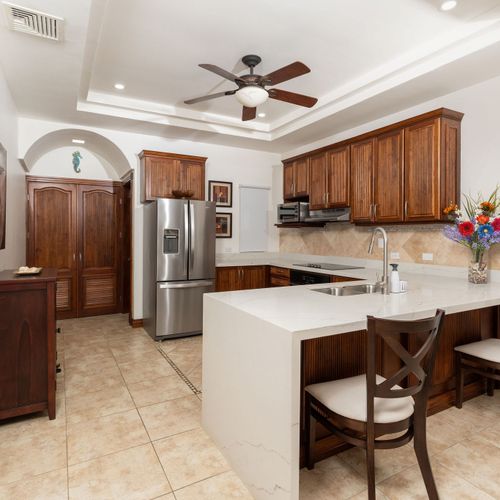 Spacious kitchen with breakfast bar and counter seating opening to bright living area at this Playa Langosta gem, Tamarindo, Costa Rica. Open concept design, natural light, ideal flow for entertaining and family gatherings.