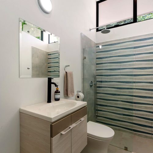 Rainfall showerhead, ocean-blue tile — five minutes in here and the whole day resets.