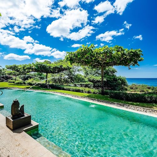 Swim-up pool bar and cascading water feature with ocean view at Playa Langosta condo in Tamarindo, Costa Rica. Shallow area for kids, deep end for laps, surrounded by lush landscaping. Perfect for cooling off after beach or surf session.