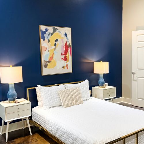 Cozy bedroom w/ bold blue accent wall & vintage-style chair