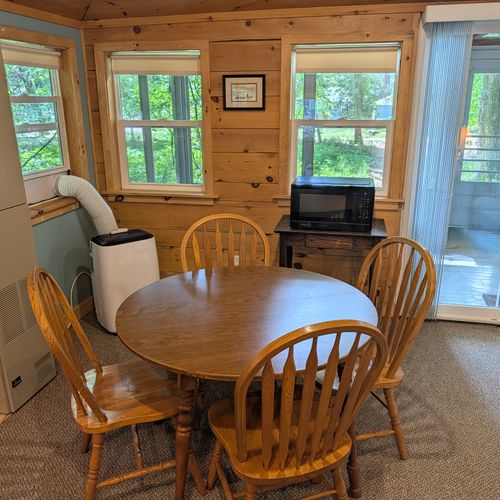 LIVING ROOM: The cute dining table in the living room with a window A/C unit and a microwave in the back