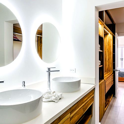 En-suite primary bathroom with a double vessel-sink vanity, backlit