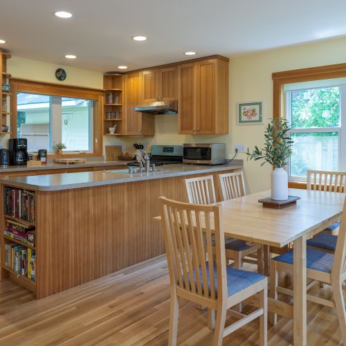 Gather around the dining table or cook with ease in the fully equipped kitchen featuring a gas range, microwave, toaster, coffee maker, electric kettle, cookware, dinnerware, and a spacious island—perfect for meals, conversation, and game nights.