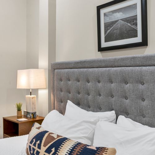 Soft lamp glow beside a plush tufted bed