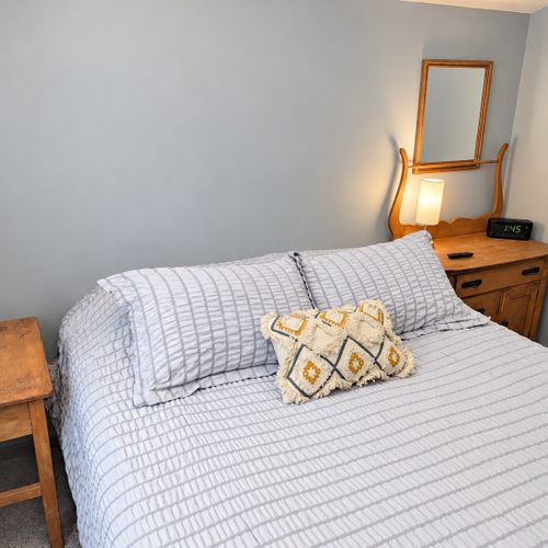 BEDROOM #1 (FIRST FLOOR):  Features a queen-size bed, nightstands, mirror, closet, and a television.
