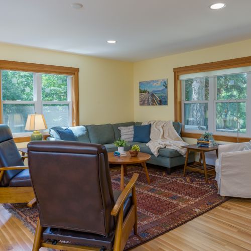 Unwind in the cozy living room with comfortable seating, large windows, and plenty of natural light—perfect for relaxing after a day of exploring.