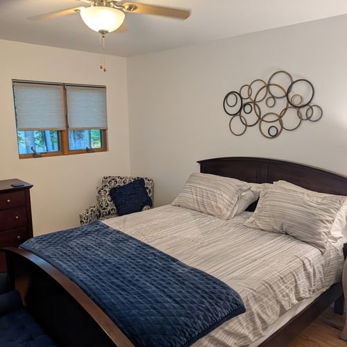 BEDROOM #3 (SECOND FLOOR):  Features a queen-size bed, nightstand, lamp, ottoman, chair, dresser, mirror, ceiling fan, closet, and private entrance to the backyard deck.