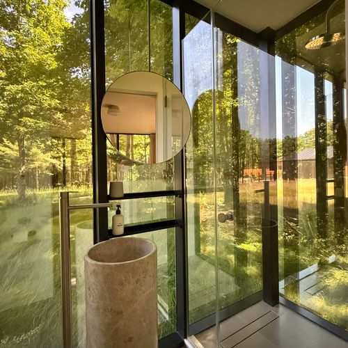 Freshen up in the glass-walled bath, where a sculptural stone basin opens right to the forest.