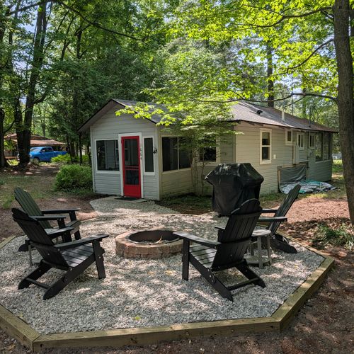 EXTERIOR: The view from the beautiful firepit and grill, aggregated with pea gravel underfoot, facing towards the cute cabin