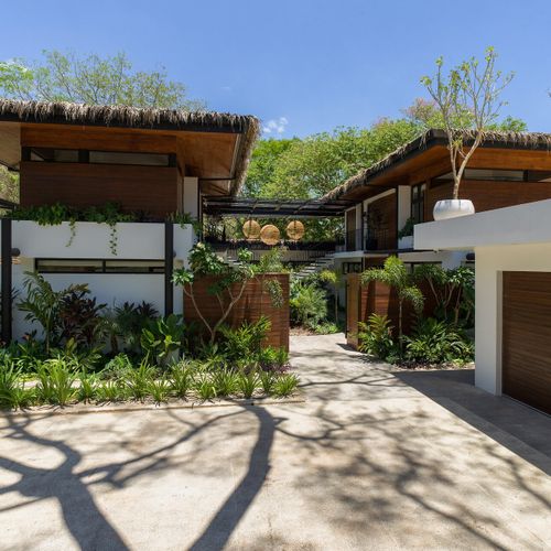 Modern tropical exterior of Casa Oso luxury villa with private garage, palapa roofs and lush landscaping in Tamarindo, Costa Rica.