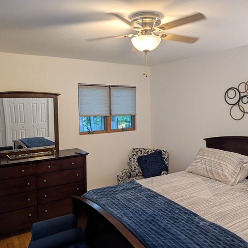 BEDROOM #3 (SECOND FLOOR):  Features a queen-size bed, nightstand, lamp, ottoman, chair, dresser, mirror, ceiling fan, closet, and private entrance to the backyard deck.