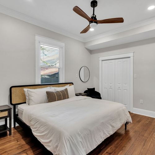 Rest easy in this calm bedroom w/ a woven headboard, crisp linens & a handy closet