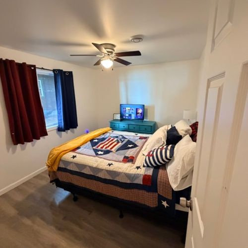 BEDROOM #1:  Features a queen-size bed, closet, dresser, television, nightstand, and a ceiling fan.
