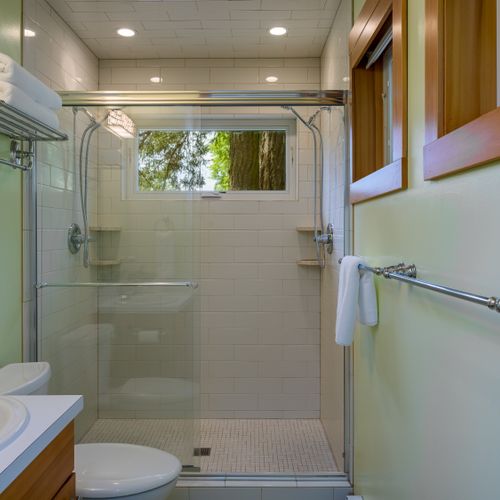 Refresh in the modern bathroom featuring a spacious glass walk-in shower, fresh towels, and a bright window that brings in natural light while maintaining privacy.