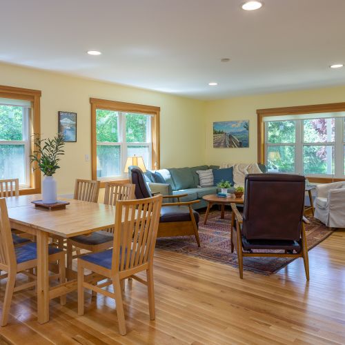 The open-concept living and dining space offers comfortable seating, a dining table for family meals, and large windows that fill the home with natural light and peaceful garden views.