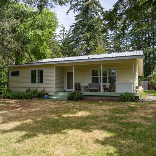 Enjoy a spacious backyard with a covered porch, comfortable seating, and plenty of room to relax, play, or gather beneath the trees.