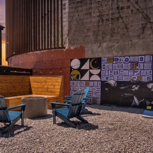 Vibrant outdoor seating area w/ firepit & art-covered walls setting the mood.
