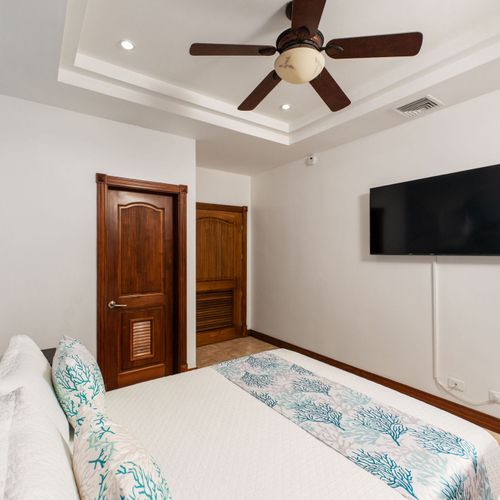 Spacious guest suite with queen bed, flat-screen TV, and private layout at Playa Langosta condo in Tamarindo, Costa Rica. Open space, natural light, comfortable seating area, ideal for extended family stays and group vacations.