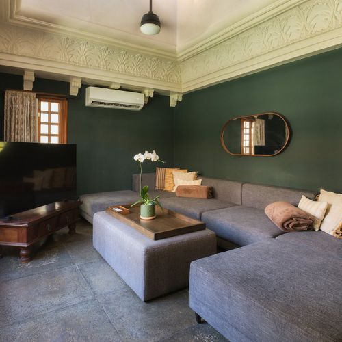 Cozy media room - deep emerald walls, ornate plaster cornice, smart TV, low gray sectional. Movie nights, sorted.